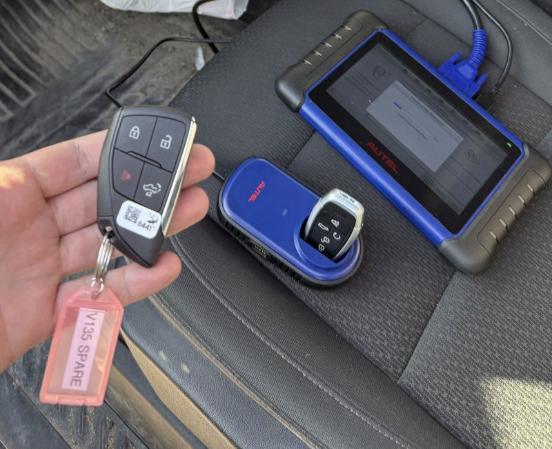 Chrysler key fob and replacement fob beside a key programming tablet